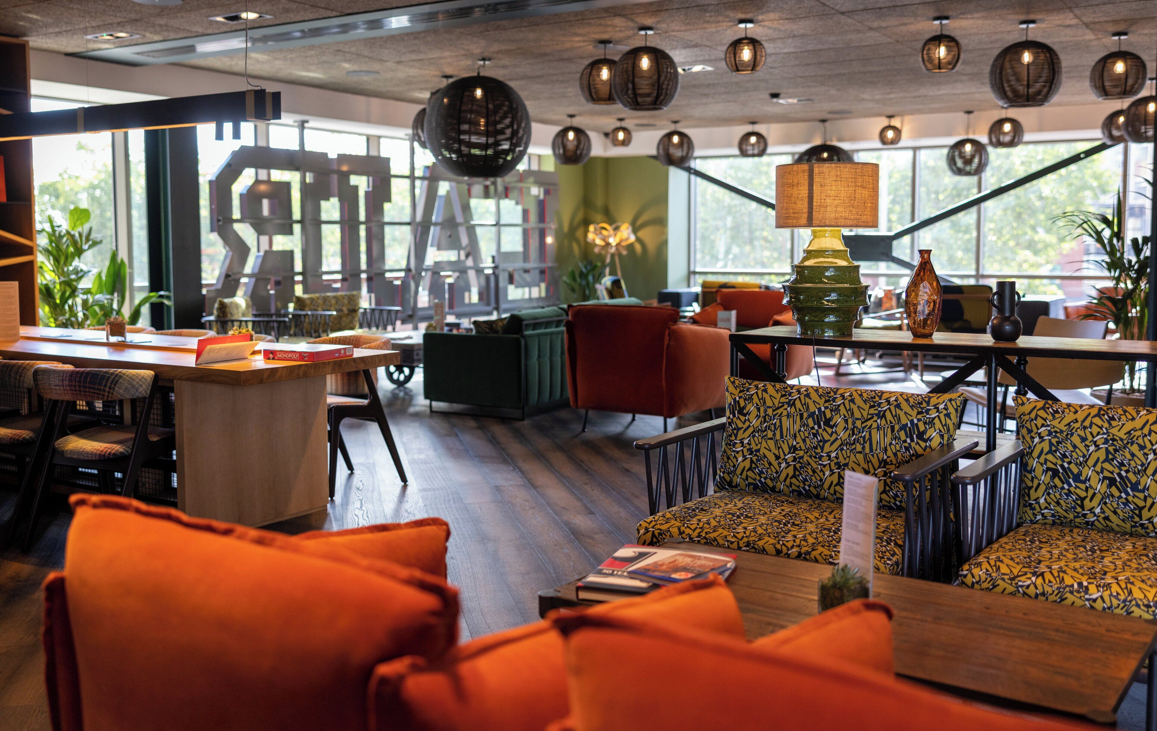 A modern interior with a wooden floor, orange seating, and a green sofa with yellow patterns.