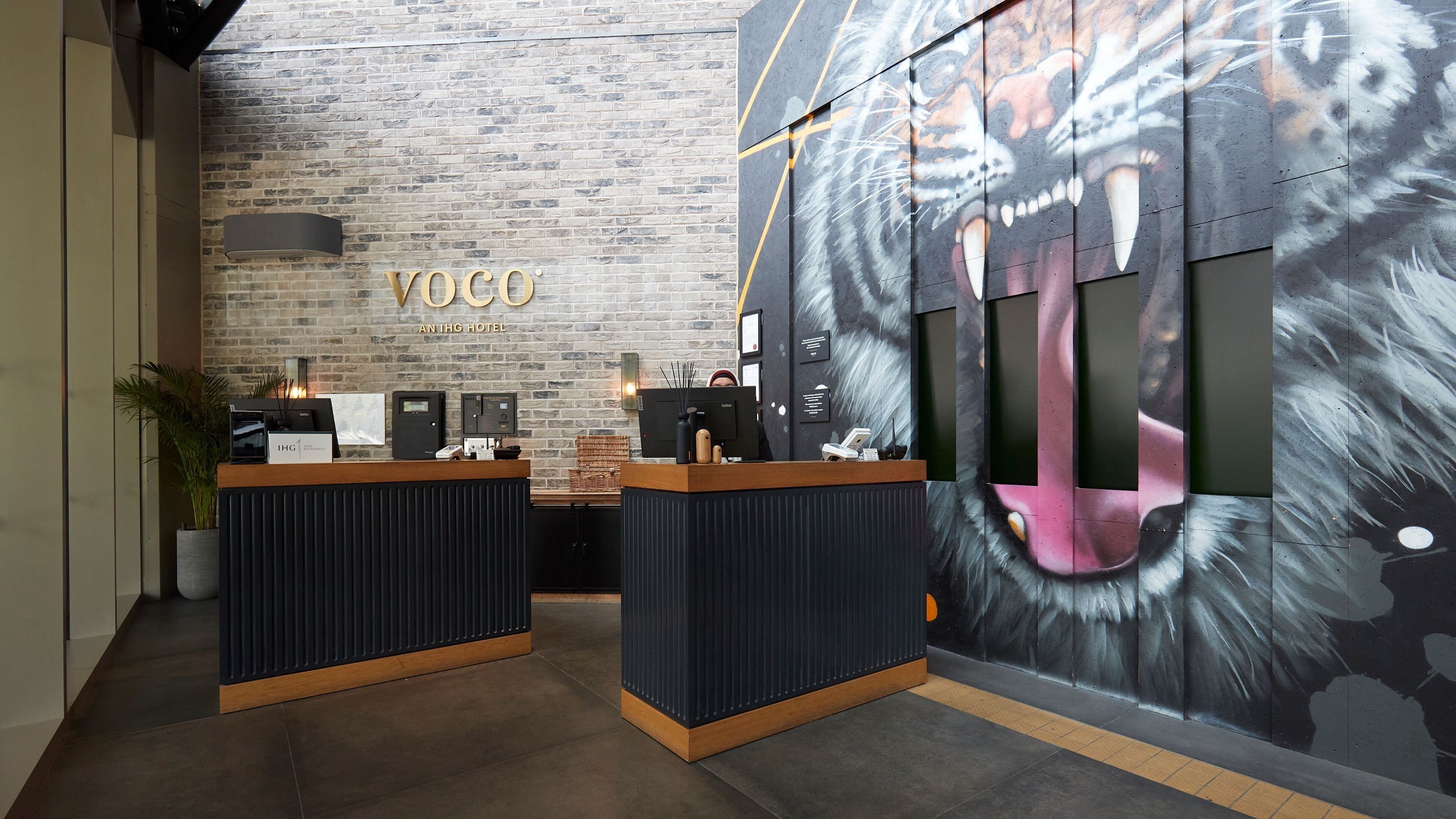 A reception desk with a modern design, a brick wall, and a large mural of a mythical creature.