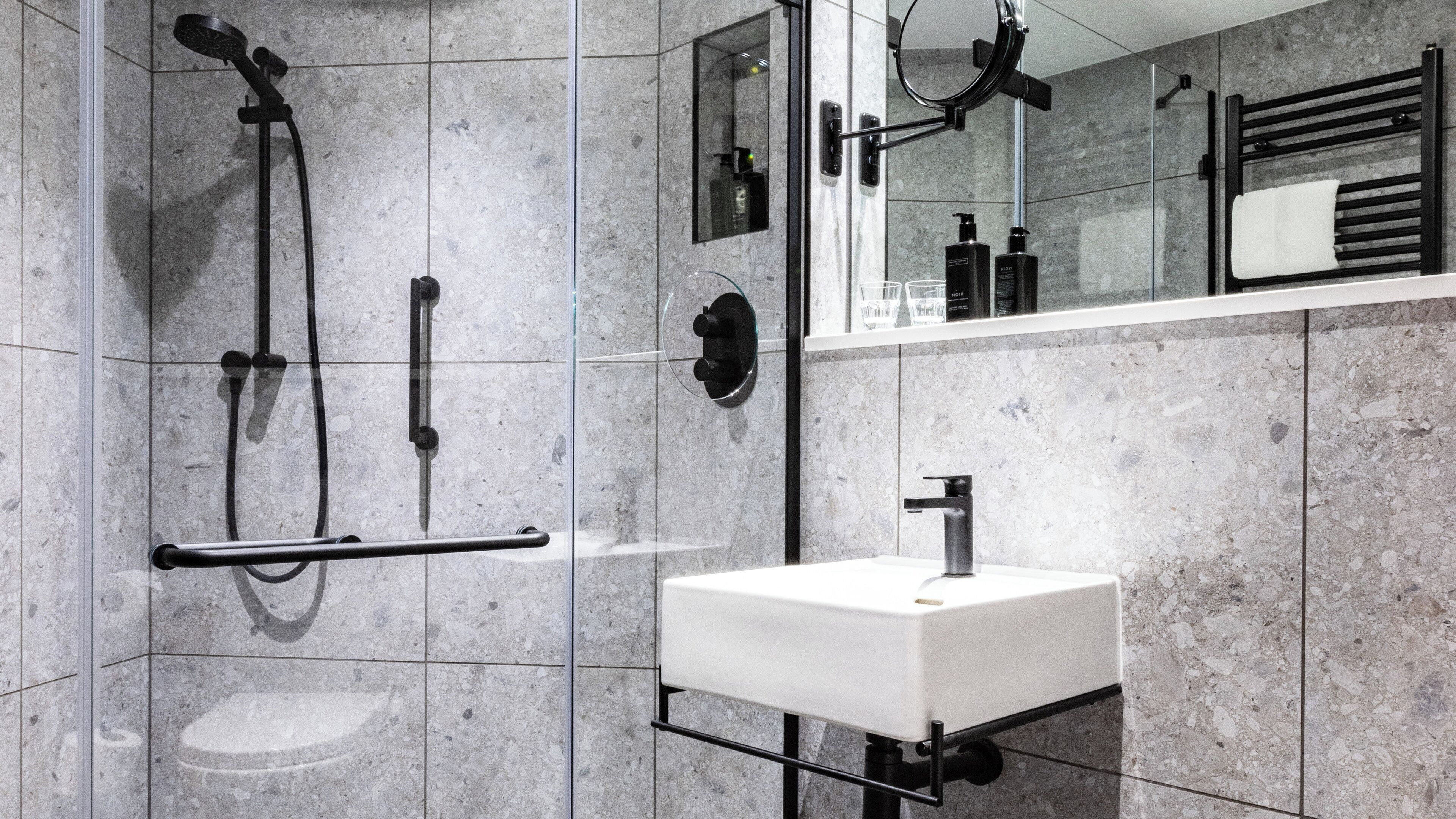 A modern bathroom with a shower, a sink, and a mirror.