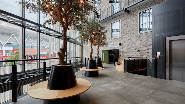 An indoor area with modern furniture, large windows, and a brick wall. - voco Leicester by IHG (Leicester)