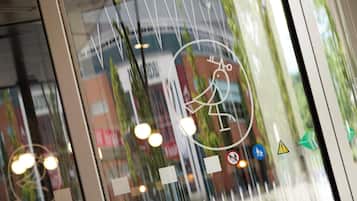 A view through a window with a reflection of a building and a sign with a pedestrian symbol.