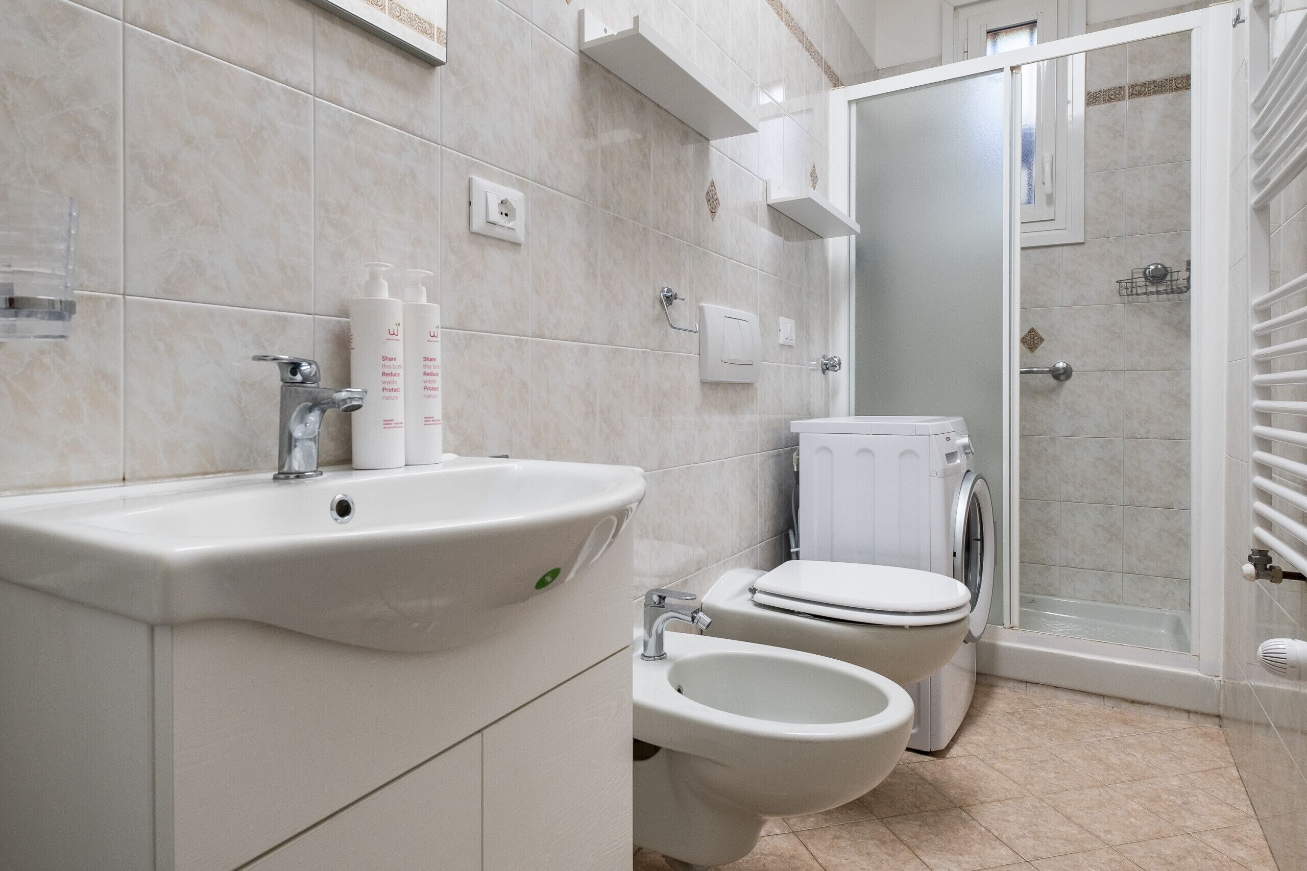 Un baño moderno con lavamanos, bidé, inodoro y zona de ducha.