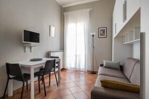 Un espace de vie compact comprenant un coin repas, un canapé, un téléviseur et un radiateur.