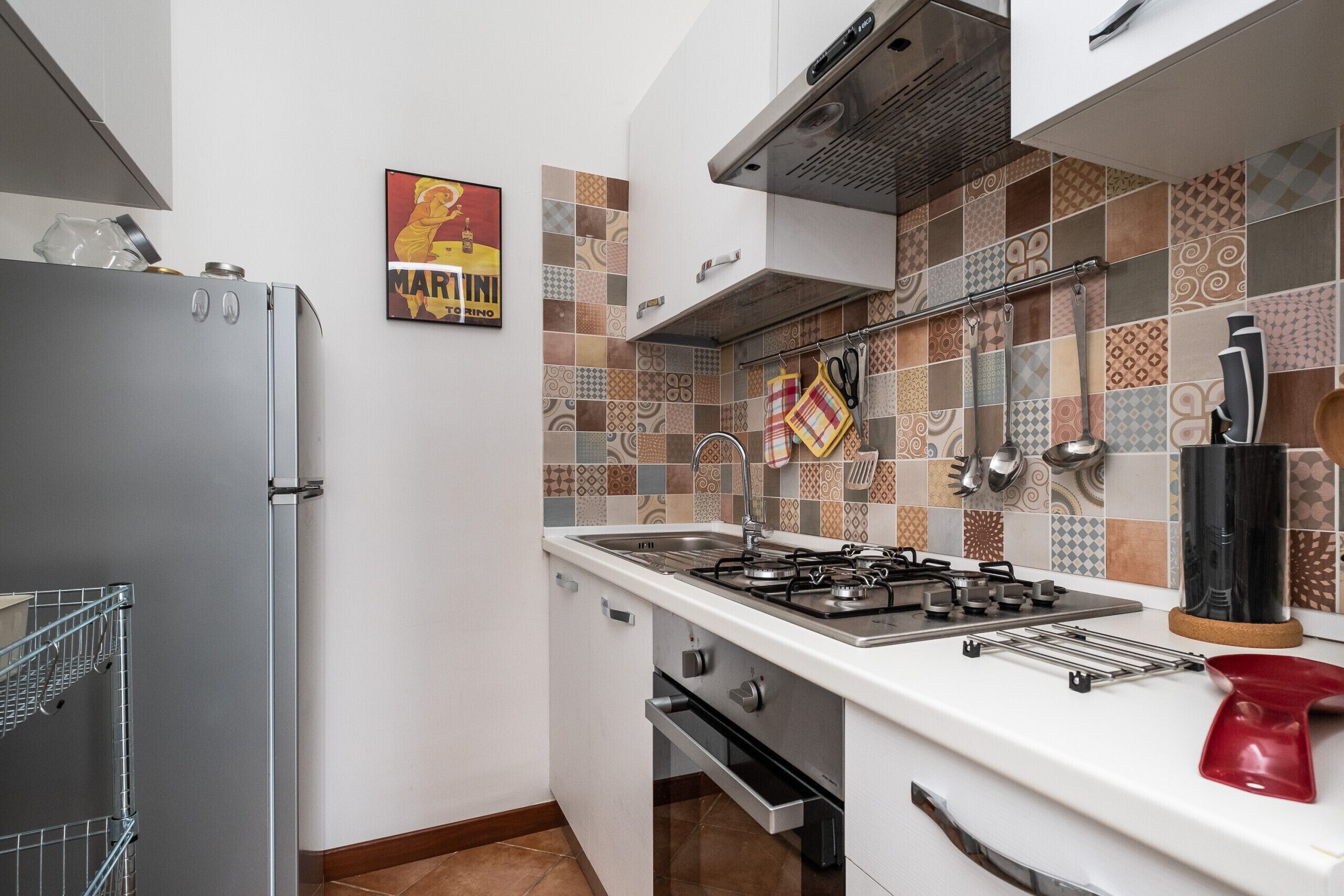 Une cuisine équipée d’une cuisinière à gaz, d’appareils électroménagers en acier inoxydable et d’un dosseret carrelé.