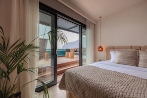 A bedroom with a large bed, a sliding glass door to a balcony, and a potted plant. - Asty Mykonos Hotel & Spa -World of One Hotel Group (Mykonos)