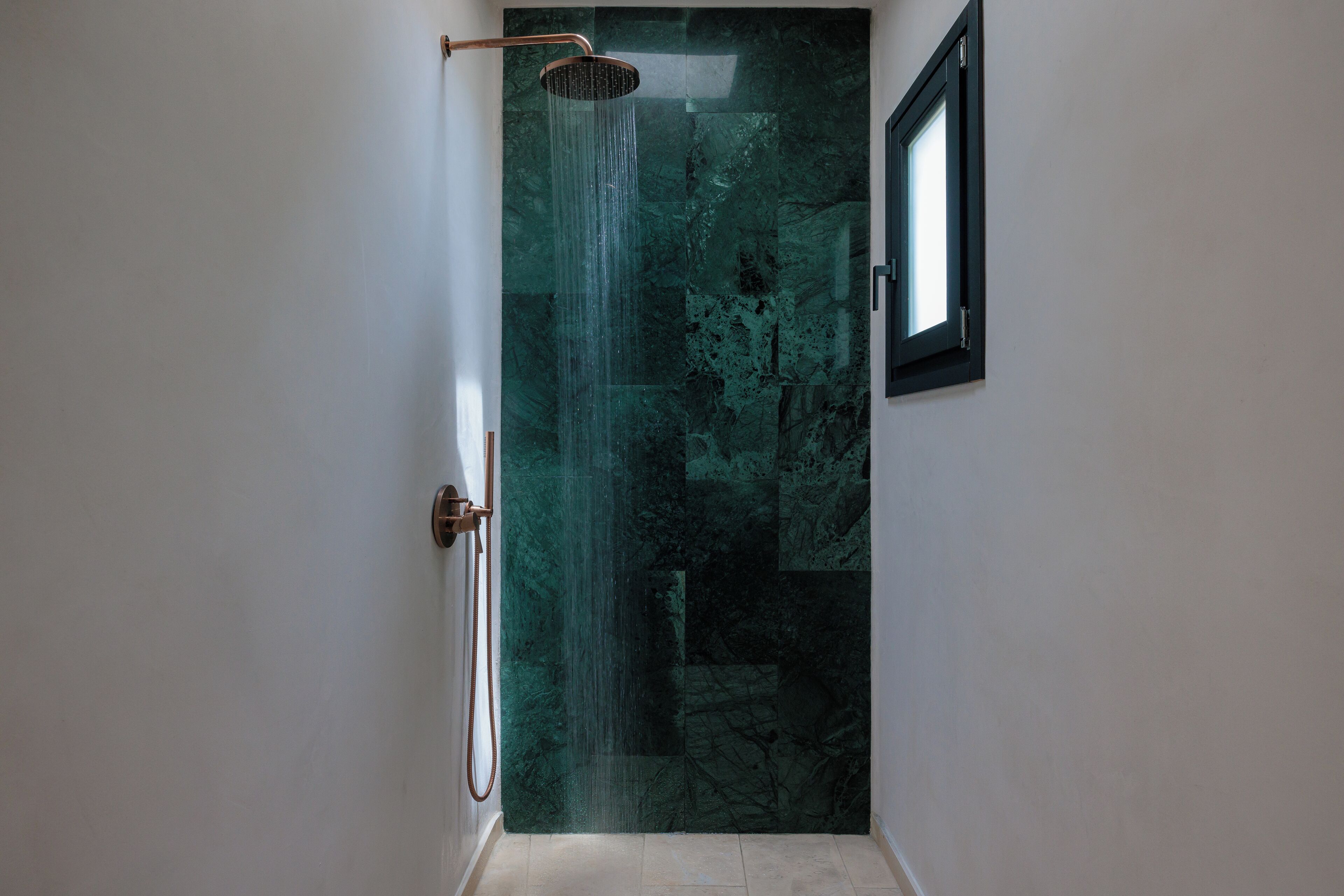 Un baño con ducha, una puerta y una ventana.