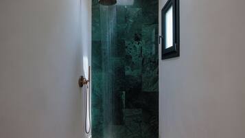Un baño con ducha, una puerta y una ventana.