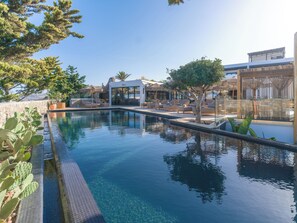 Una piscina al aire libre, sombrillas, sillones reclinables de piscina