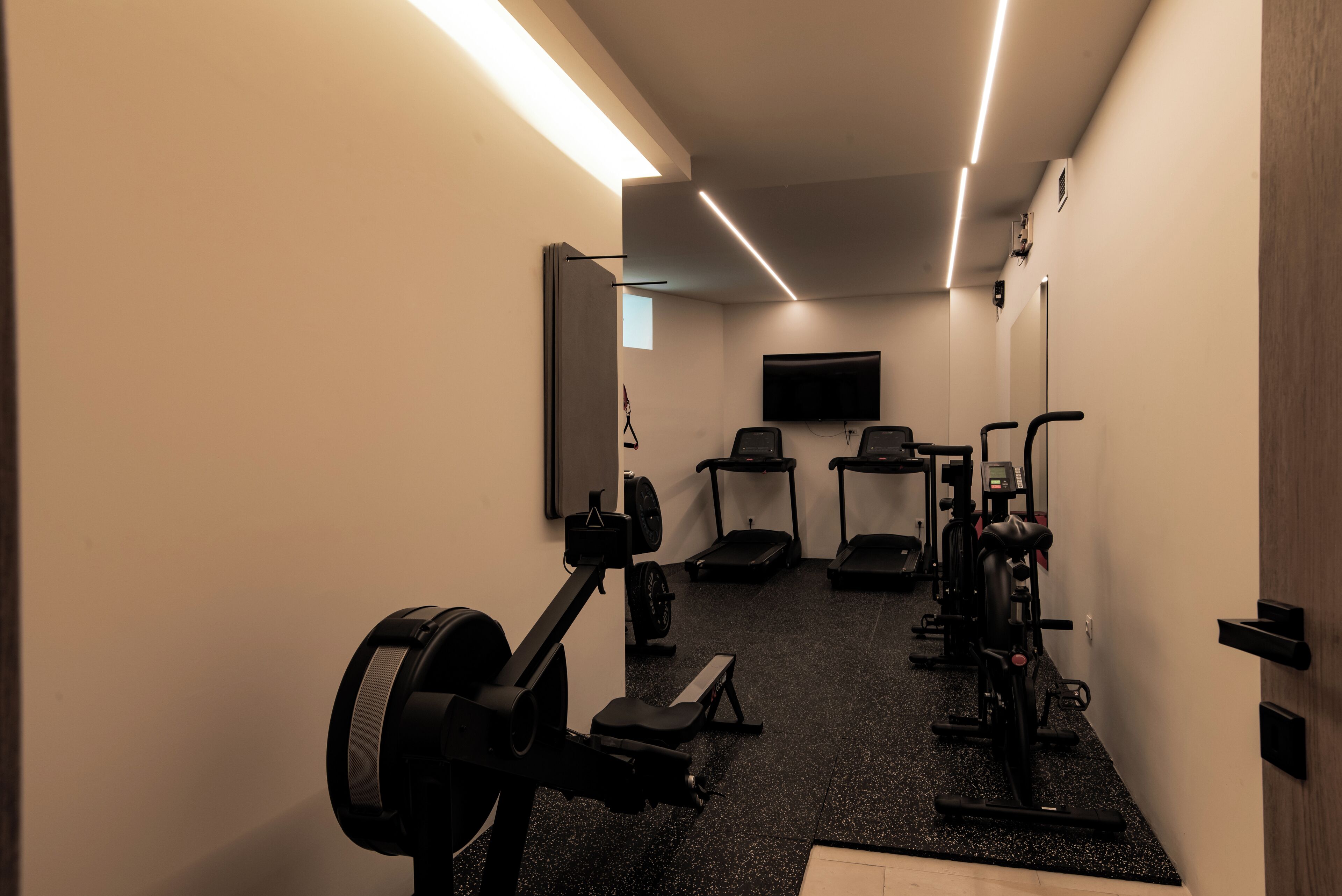 Ein Fitnessstudio mit Laufbändern, Crosstrainern und Gewichten.