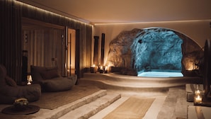 Ambiente tipo spa con una grande formazione rocciosa, area relax e vasca da bagno.