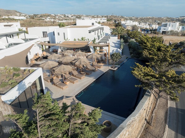 Un moderno resort con piscina, tumbonas y sombrillas.