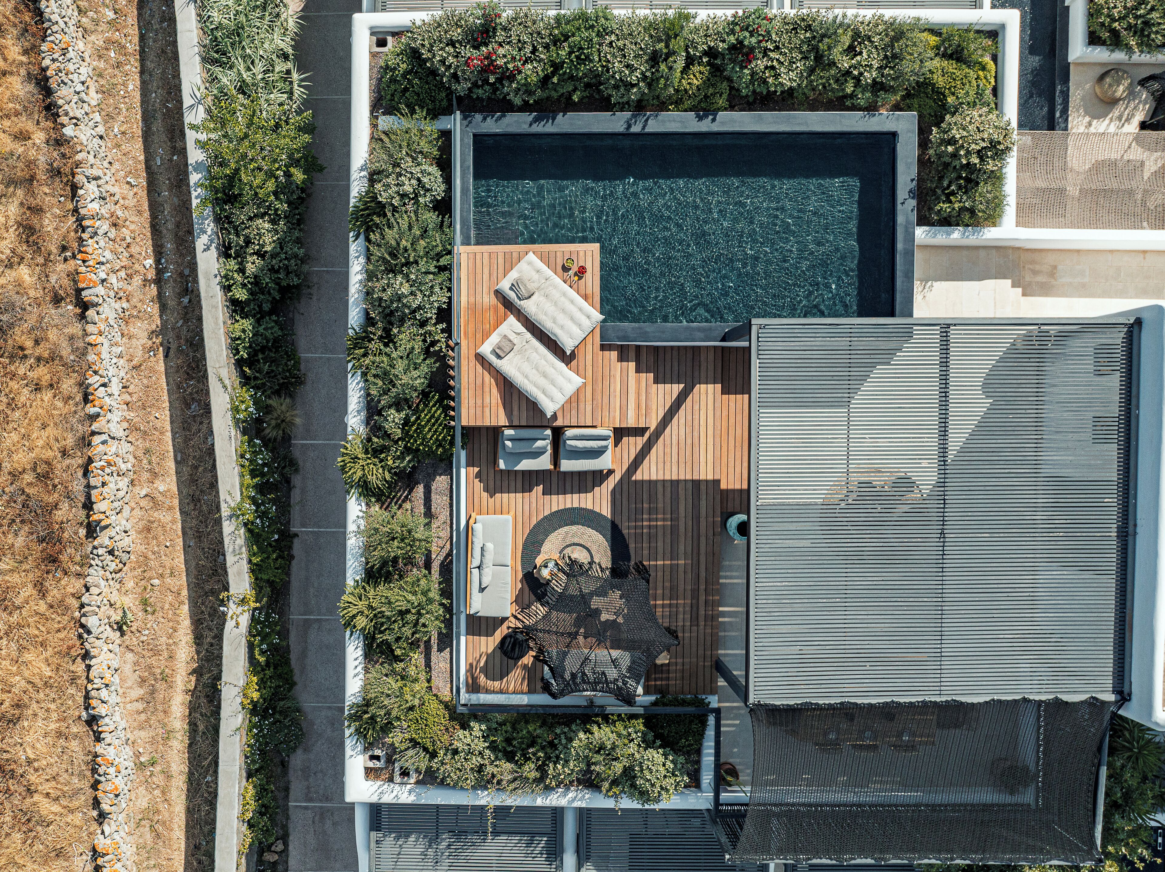 Vista aérea de una casa moderna con piscina en la azotea, terraza de madera y zona de estar al aire libre.