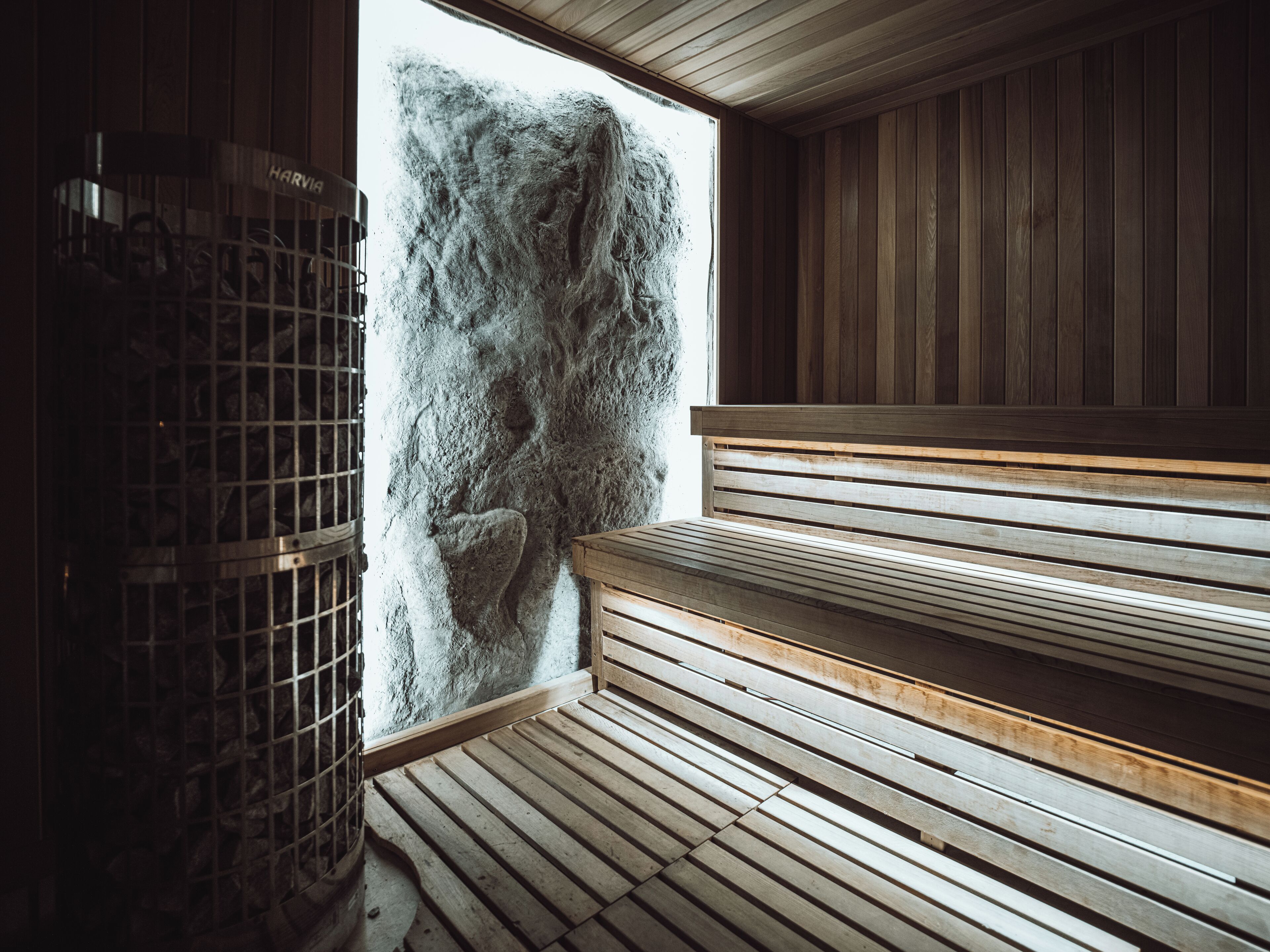 A sauna room with wooden benches and a stone wall.