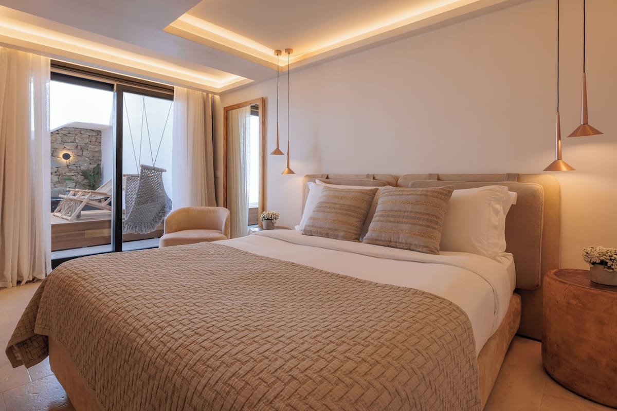 Un dormitorio moderno con una cama grande, una zona de estar con una silla y vistas al exterior.