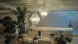 Un interno moderno con un'area salotto rotonda, grandi piante in vaso e un lampadario decorativo.
