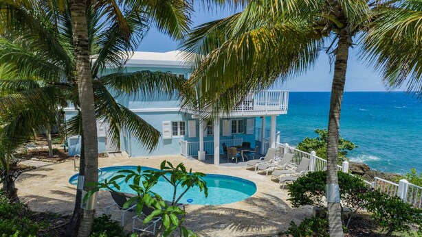 A beachfront property with a pool, lounge chairs, and a view of the ocean. - Cliffside at Cane Bay - 3 bed/ 4 bath seaside home with private pool. (Cane Bay beach)