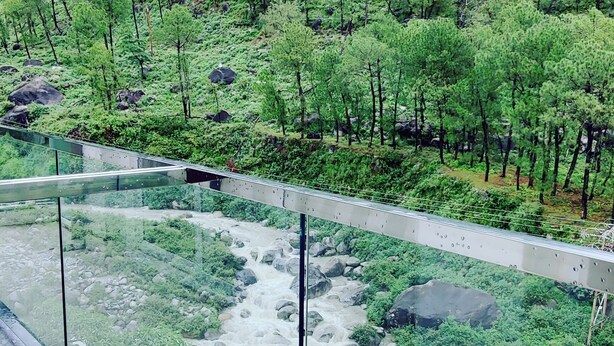 A river with a bridge, surrounded by greenery and mountains. - Manuni Inn - Riverside Hotel (Dharamshala)