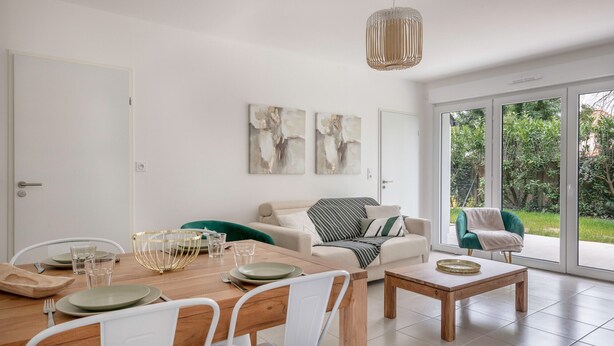 Una sala de estar moderna con comedor, que incluye un sofá, una mesa de centro y un amplio ventanal con vista a áreas verdes.