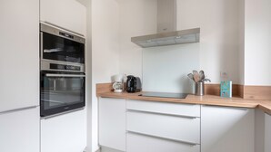 Una cocina moderna con electrodomésticos de acero inoxidable, encimera de madera y armarios blancos.