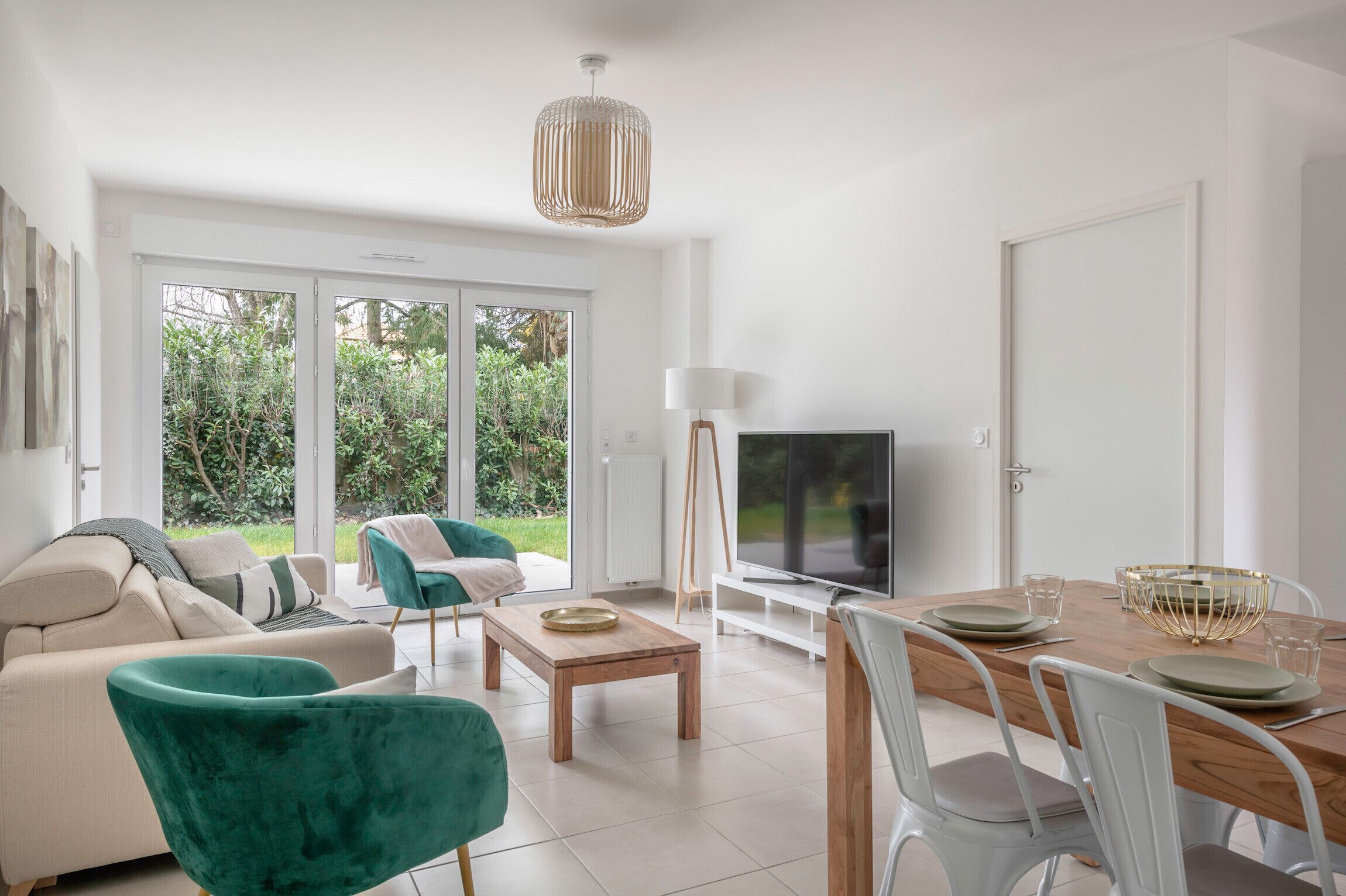 Ein modernes Wohnzimmer mit einer Couch, einem Couchtisch und einem Fernseher. Es gibt einen Essbereich mit einem Tisch für zwei Personen.