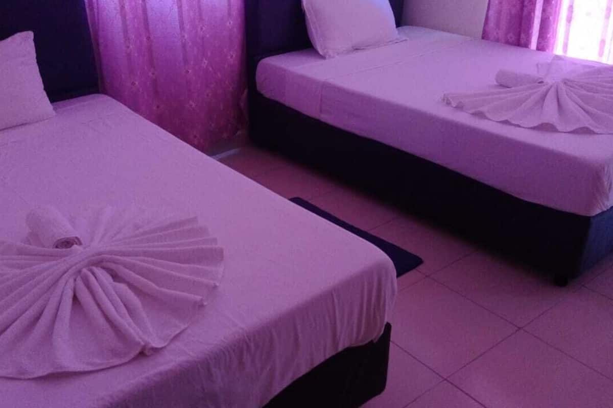 Two beds with white linens and a decorative pillow arrangement.