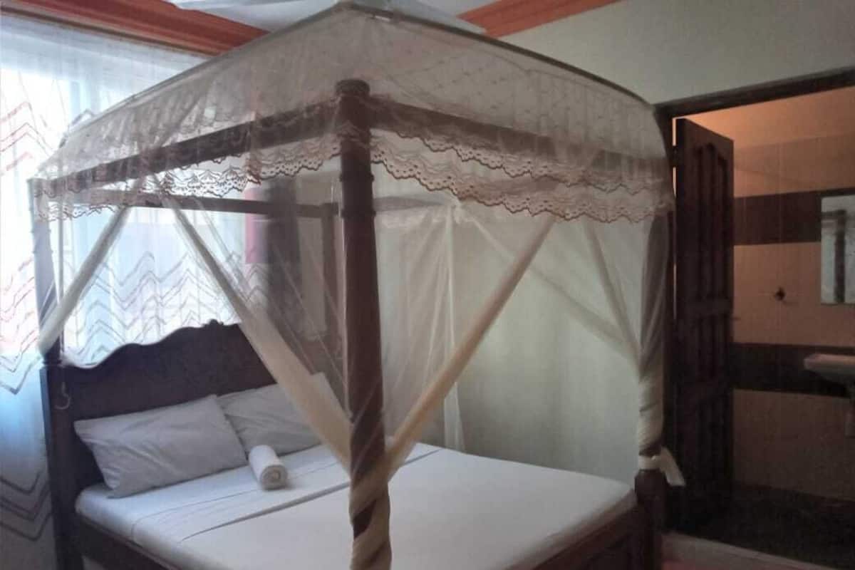 A four-poster bed with a canopy, a wooden headboard, and a white bedspread.