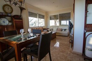 A dining area with a glass-top table, chairs, and a clock on the wall.