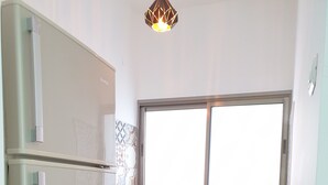 A compact kitchen with a refrigerator, cabinets, and a window. - City Center Rooms (Nazareth)