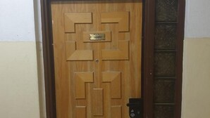 A wooden door with a geometric pattern and a brass plate, set in a white and beige wall. - City Center Rooms (Nazareth)