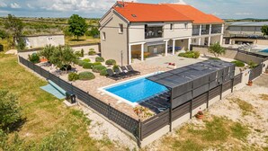 A two-story house with a swimming pool, outdoor seating, and a covered patio area.