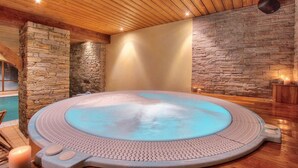 Ein Whirlpool mit Steinwand, Holzboden und einer Steinsäule.