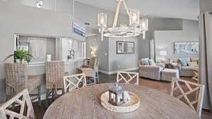 Amplia sala de estar con candelabro, muebles de mimbre y una mesa de comedor con un candelabro como centro.