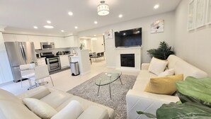 A modern living room with a white sofa, a glass coffee table, and a fireplace. - ★ Beautiful 3 Bedroom Home - Parking, Wi-fi, near Hwy 401, 6 Beds available (Cambridge)