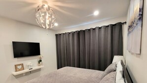A bedroom with a bed, a flat-screen TV, a ceiling light fixture, and a window with curtains. - ★ Beautiful 3 Bedroom Home - Parking, Wi-fi, near Hwy 401, 6 Beds available (Cambridge)