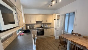 Eine moderne Küche mit Holzschränken, einem eingebauten Backofen und einem Essbereich mit einem Holztisch und Stühlen.