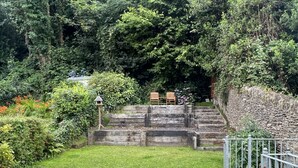 Eine Steintreppe führt zu einem Sitzbereich mit zwei Holzstühlen.