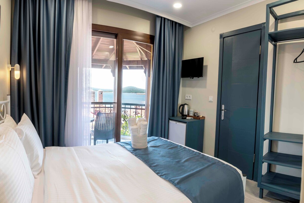Ein Hotelzimmer mit Bett, Fernseher, Schreibtisch und Blick ins Freie.