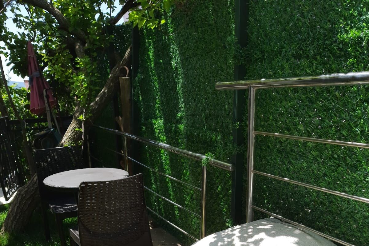 An outdoor seating area with a table and chairs, a stone bench, and a metal railing.