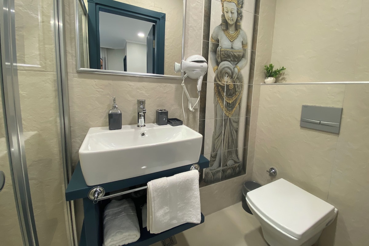 Un baño con lavamanos blanco, un espejo, secador de pelo y un inodoro.