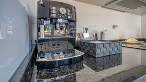 A modern kitchen with a coffee machine, a kettle, and a small island with seating. - Central Suites Arouca (Arouca)