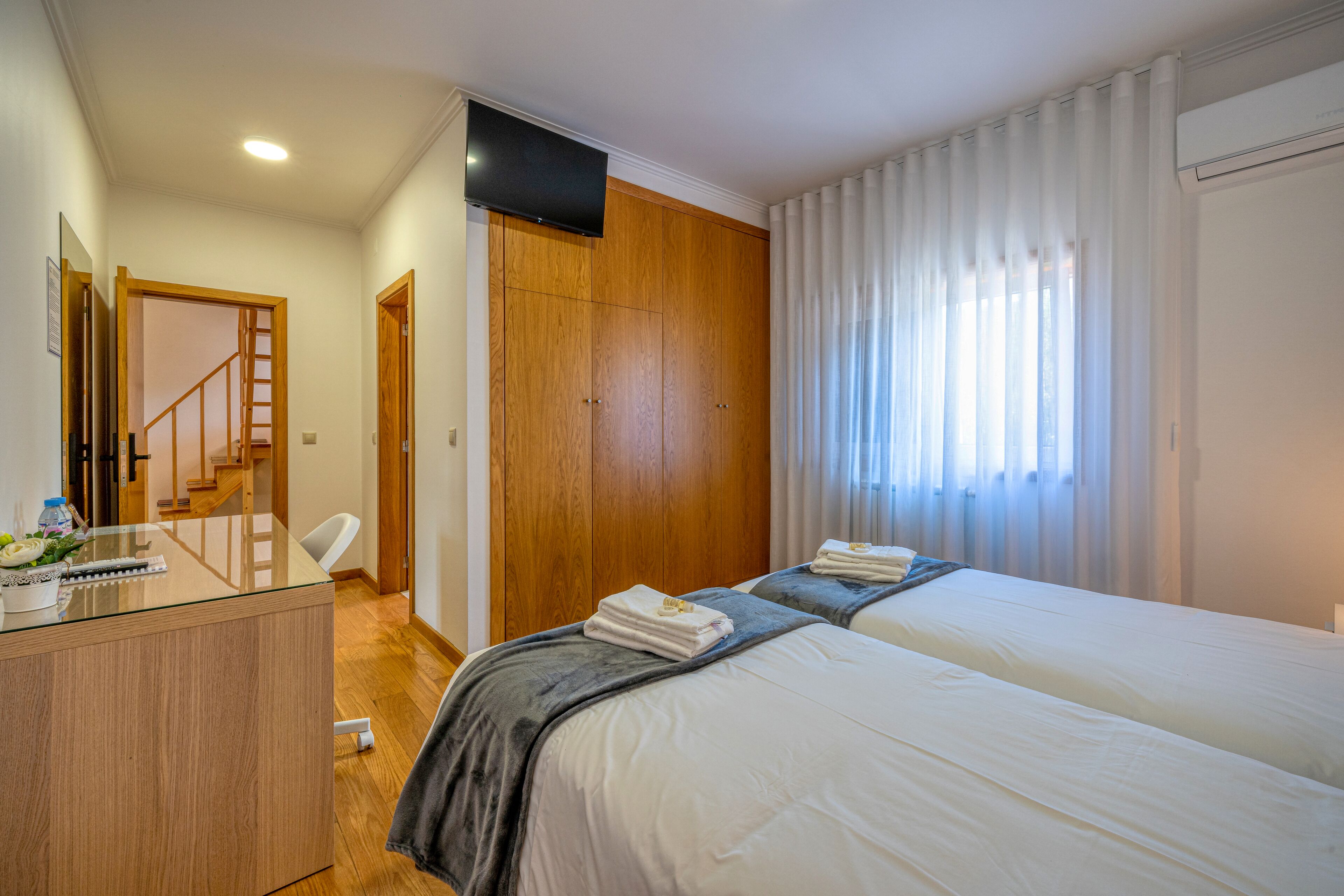 Habitación de hotel con escritorio, dos camas, televisión y una escalera.