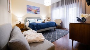 Een moderne slaapkamer met een bed, nachtkastjes, een stoel, een bureau en een schilderij aan de muur.