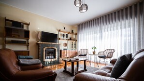 Een woonkamer met leren banken, een open haard, een televisie en een boekenkast.