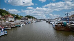 Un puerto con barcos amarrados a lo largo de la costa, rodeado de edificios y vegetación.