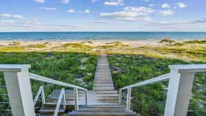 A wooden boardwalk leading to a beach with a clear view of the ocean.