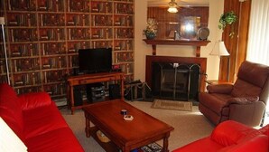 Un salon avec une cheminée, une bibliothèque, un canapé rouge et un téléviseur.