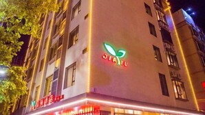 A building with a prominent green and red sign reading "JIAYU" and a red sign below it that appears to be a restaurant or cafe. - Jiayu Business Hostel (Sihui)