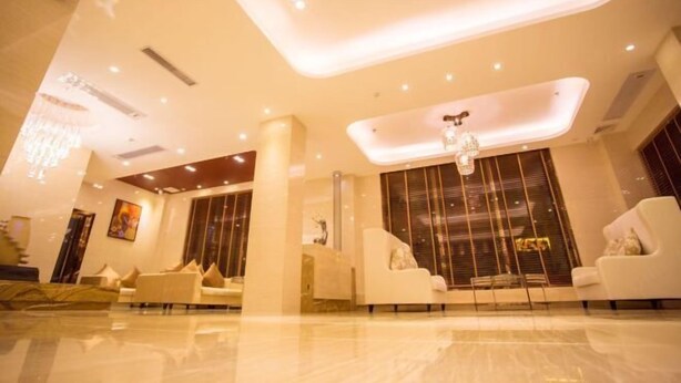 A modern lobby with a high ceiling, recessed lighting, and a chandelier. There are several seating areas with sofas and a large window with blinds. - Jiayu Business Hostel (Sihui)