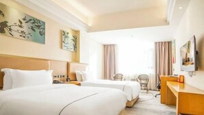 A hotel room with two beds, a desk, a chair, and artwork on the walls. - Jiayu Business Hostel (Sihui)
