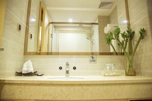A bathroom with a sink, mirror, and a plant.